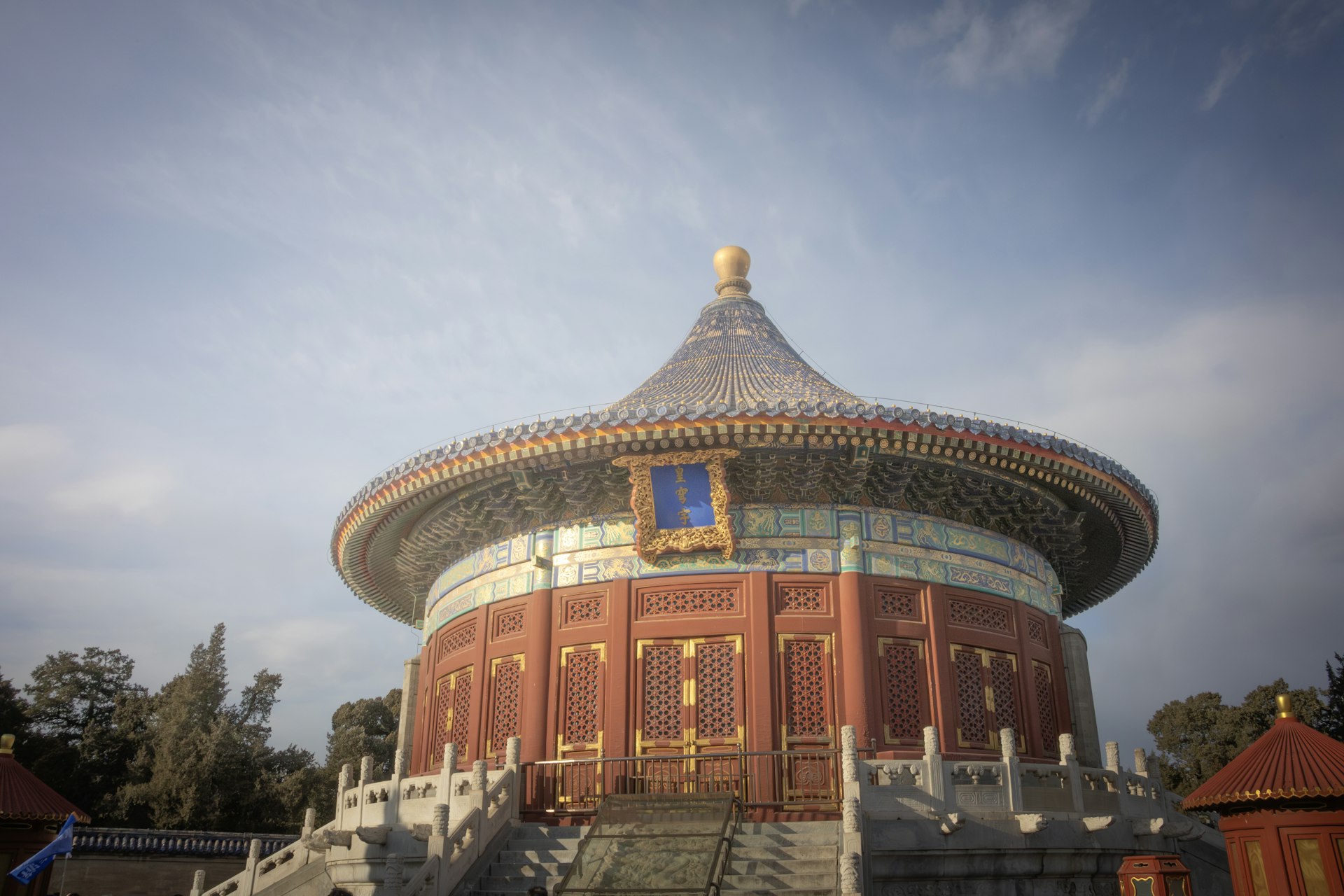 A circular blue-tiled hall at the Temple of Heaven against a clear sky, red-lacquer walls and a gold finial