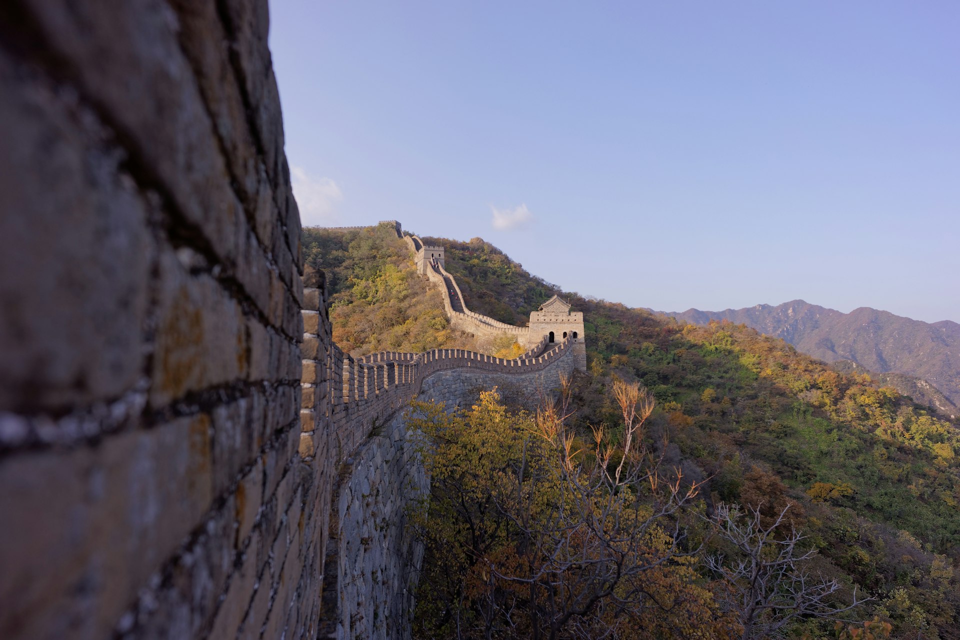 The Forbidden City's golden roofs at dusk with the Great Wall snaking over the mountains beyond — Beijing hero shot