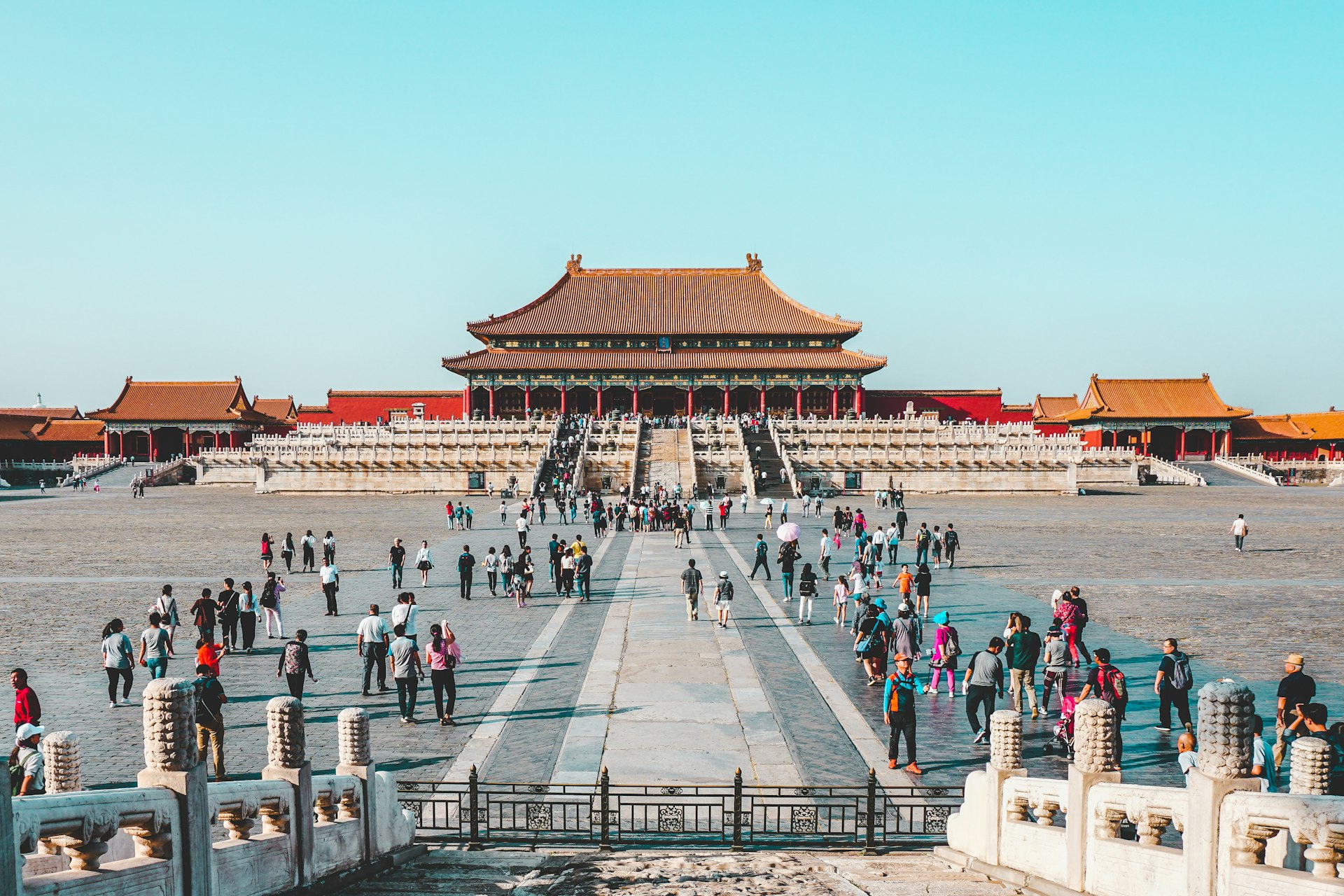 Forbidden City rooftops under a crisp deep-blue autumn Beijing sky, golden ginkgo leaves in the foreground