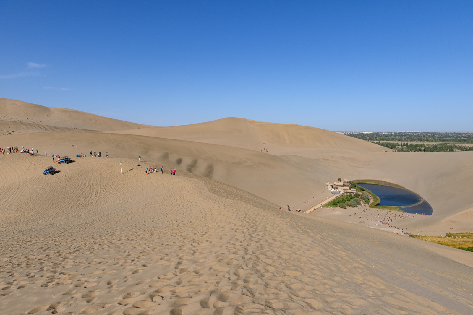 Camel caravan cresting the Mingsha sand dunes at sunset above the Crescent Lake oasis, Dunhuang