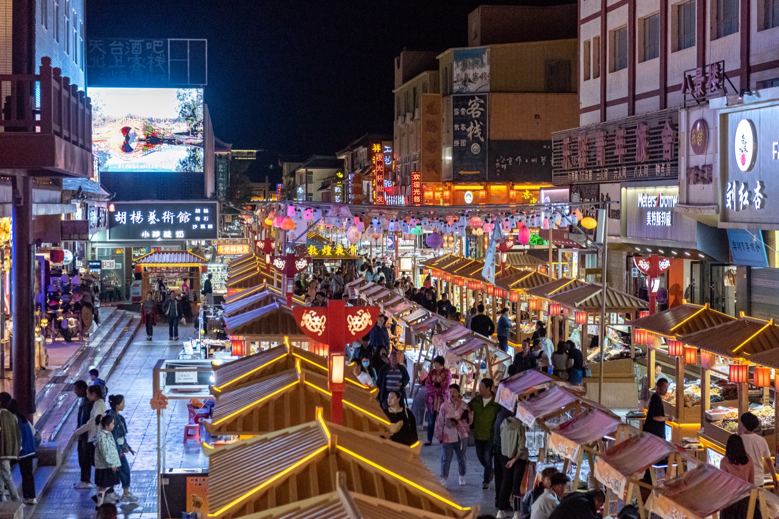 Shazhou Night Market after dark — lantern-strung food stalls, sizzling lamb skewers over coals, crowds of diners