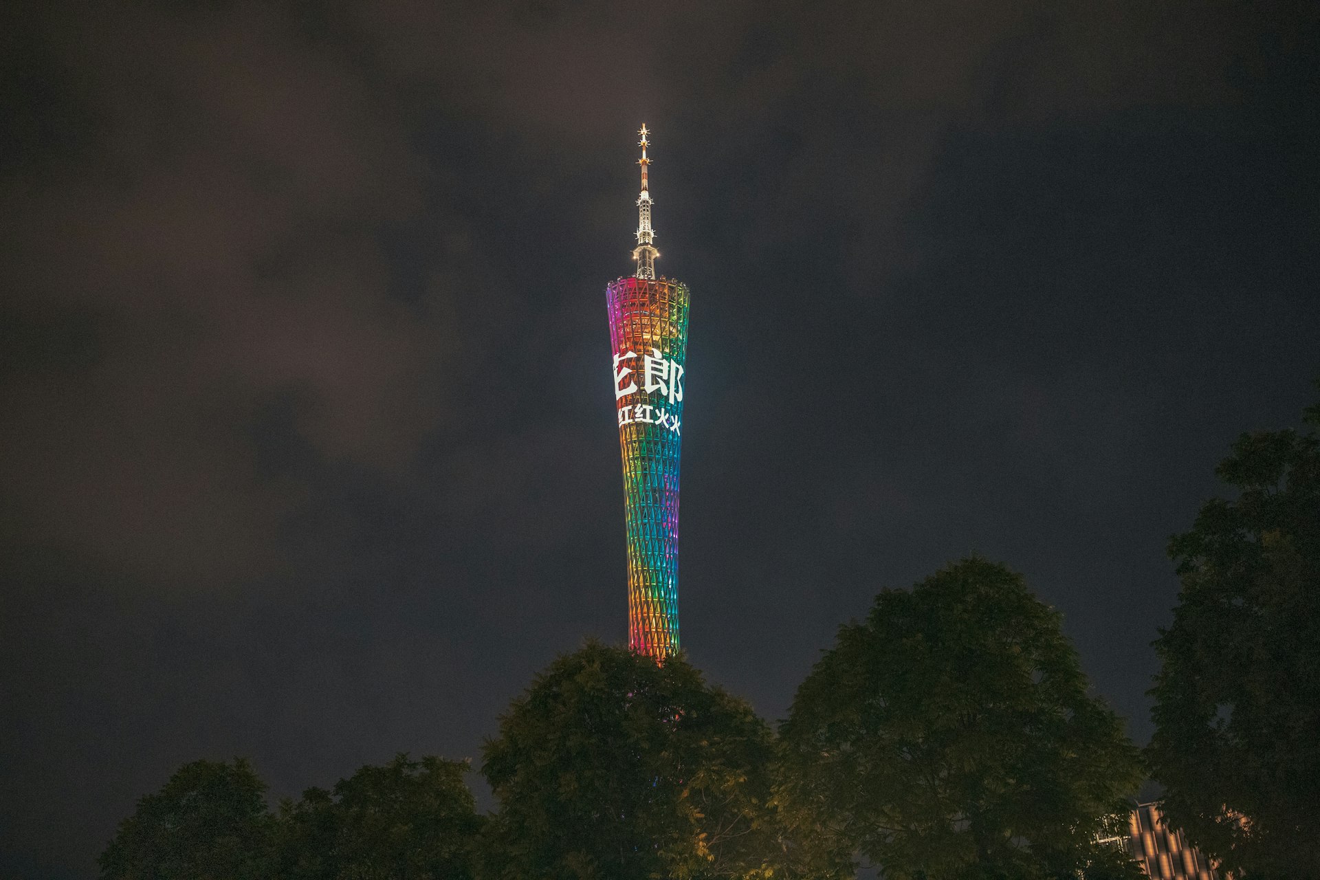 Canton Tower glowing pink-to-violet above the Pearl River at dusk, neon riverfront reflecting on the water