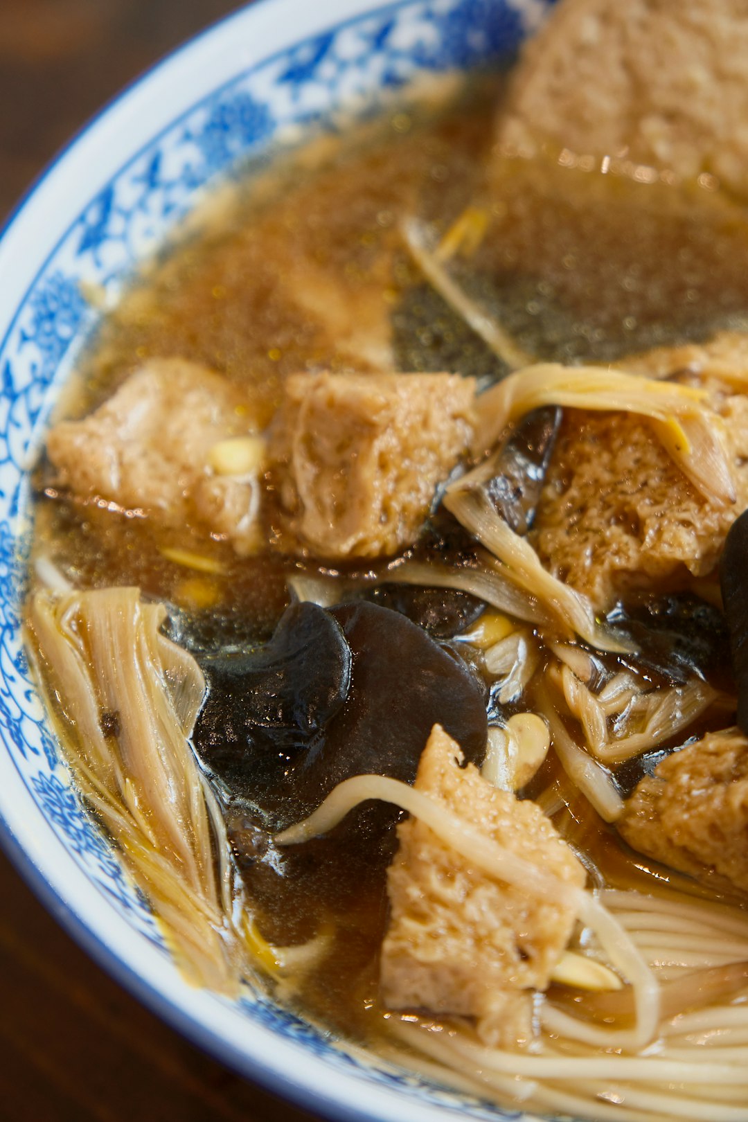 A steaming bowl of Guilin rice noodles — silky white mifen topped with braised beef, pickled bamboo, and chili oil