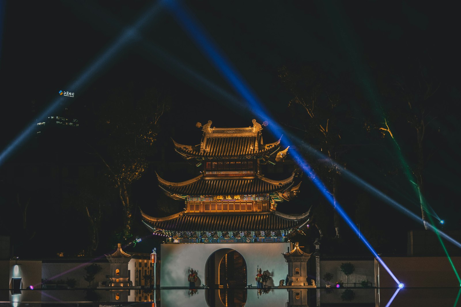Qinhuai River night cruise — traditional wooden boat gliding past neon-lit Confucius Temple buildings reflected in the water