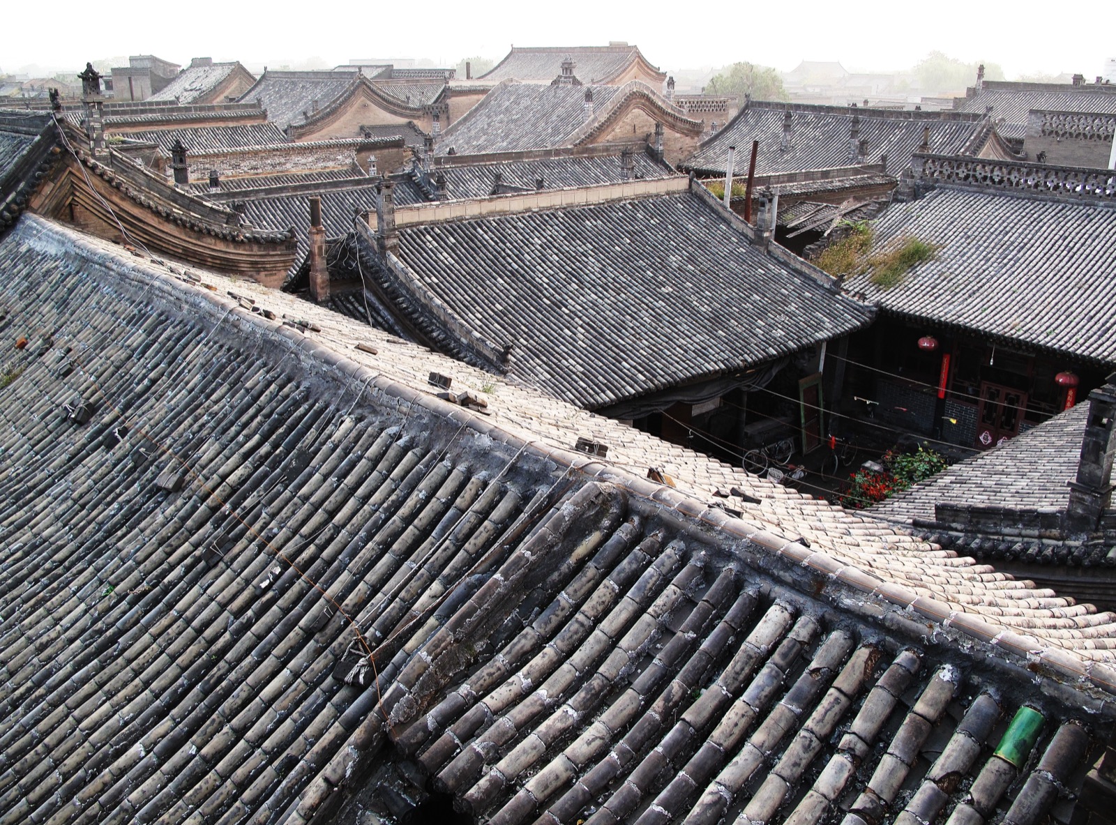 Pingyao's illuminated Ming-dynasty city wall and watchtowers at dusk, the grey-tiled old town glowing below