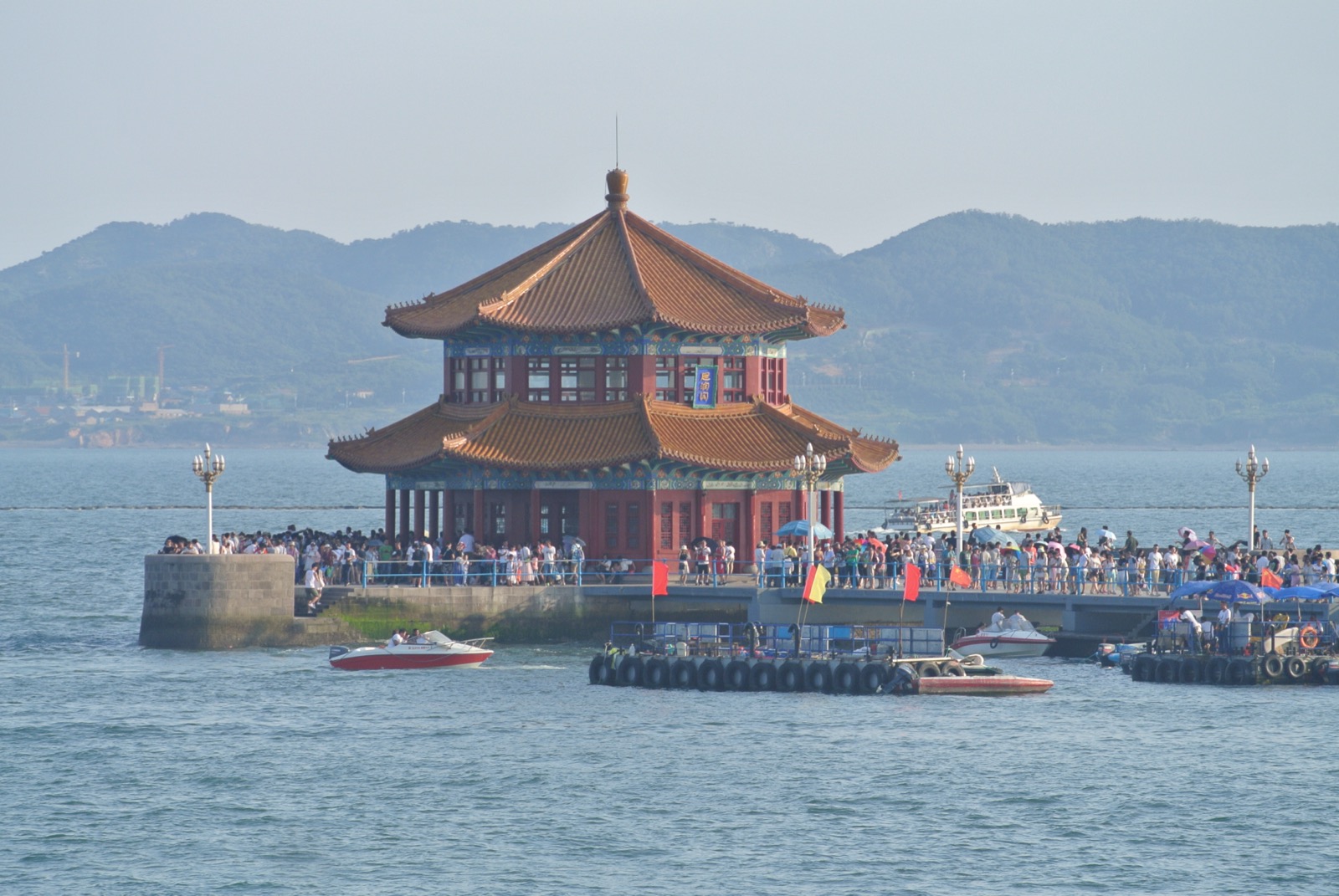 Qingdao's red-roofed German old town tumbling down to the blue Yellow Sea, St. Michael's spires above — hero shot