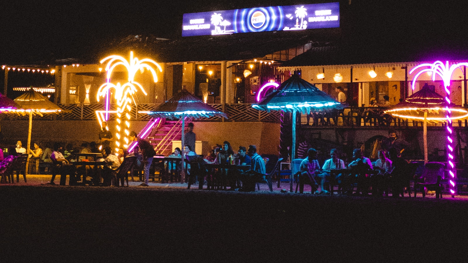 Dadonghai's seaside bar street at night — neon, outdoor seating, live music and seafood stalls by the beach